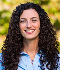 Woman with brown curly hair and blue shirt smiling